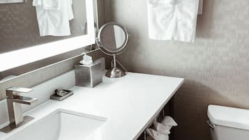 Ein Badezimmer mit einem weißen Waschbecken, einem Spiegel, einem Handtuchhalter und einer Toilette.