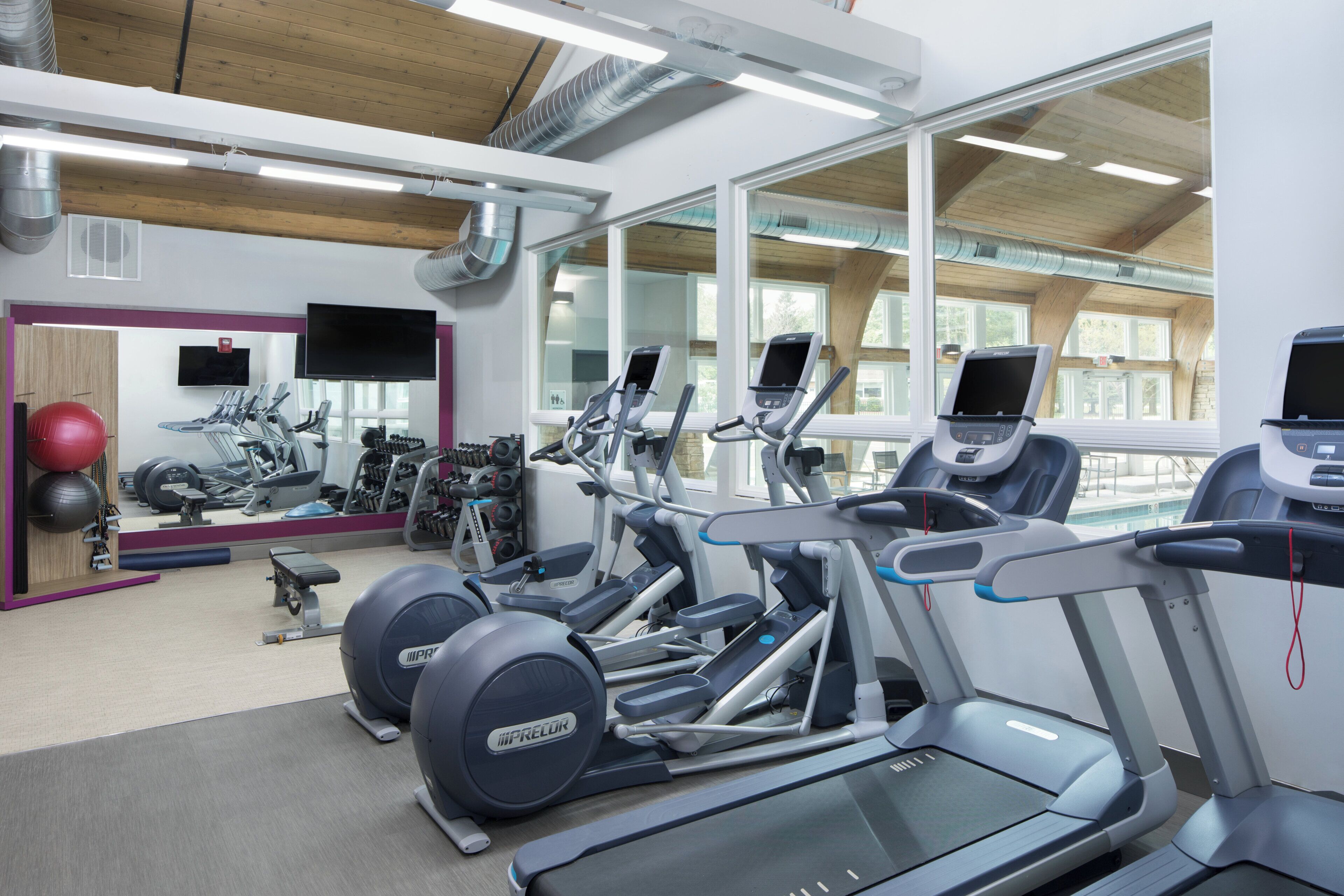 A gym with treadmills, stationary bikes, and exercise balls.