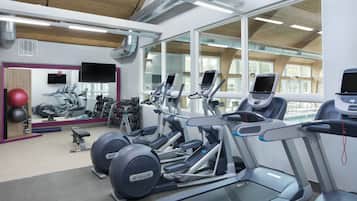 A gym with treadmills, stationary bikes, and exercise balls.