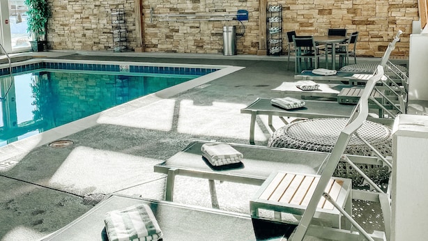 Une piscine intérieure dotée de chaises longues et d’un mur en pierre.