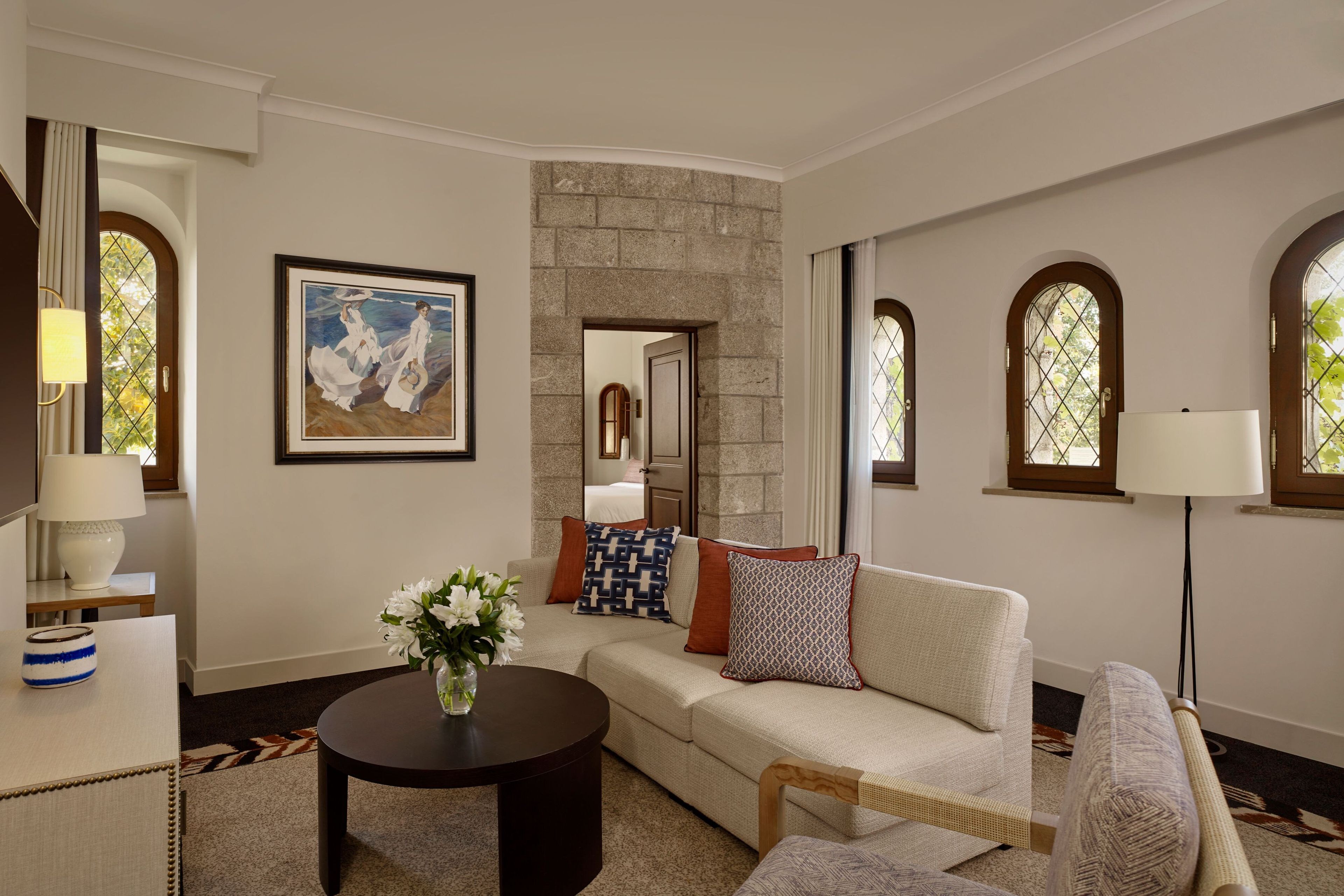 A living room with a sofa, a coffee table, a lamp, and a painting on the wall.