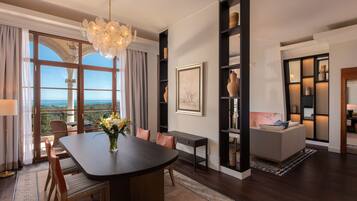 A modern living room with a dining area, a large window with a view, and a chandelier.