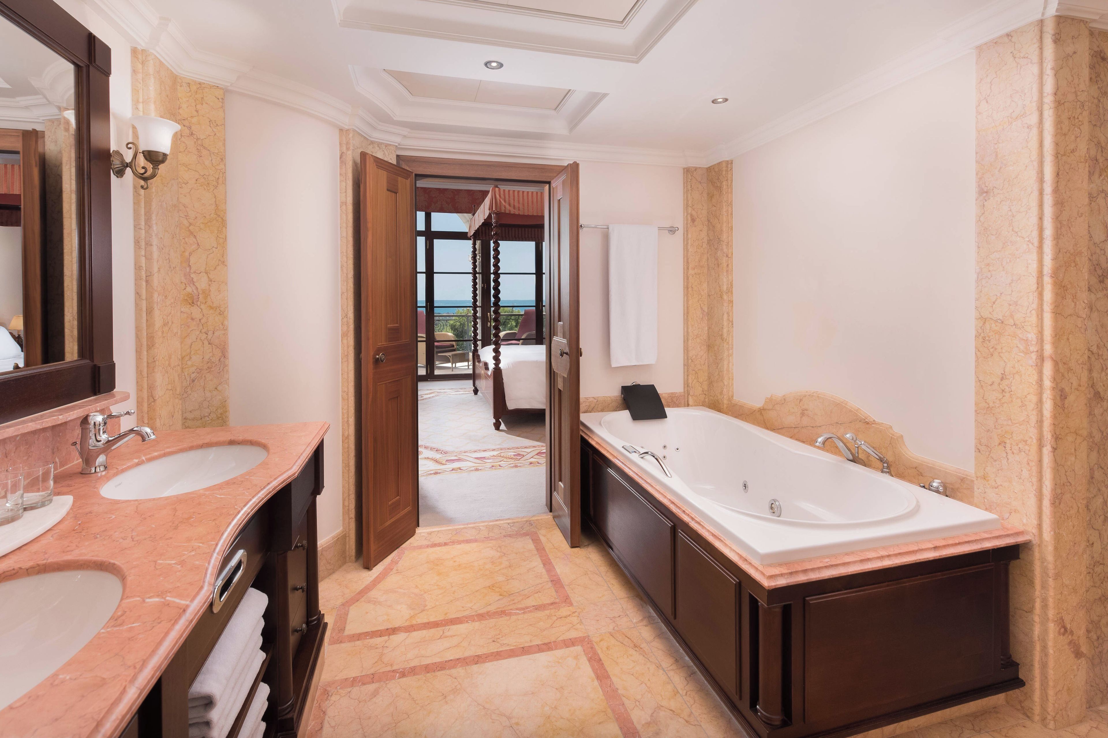 Un baño lujoso con dos lavamanos, una bañera grande y vistas a un balcón.