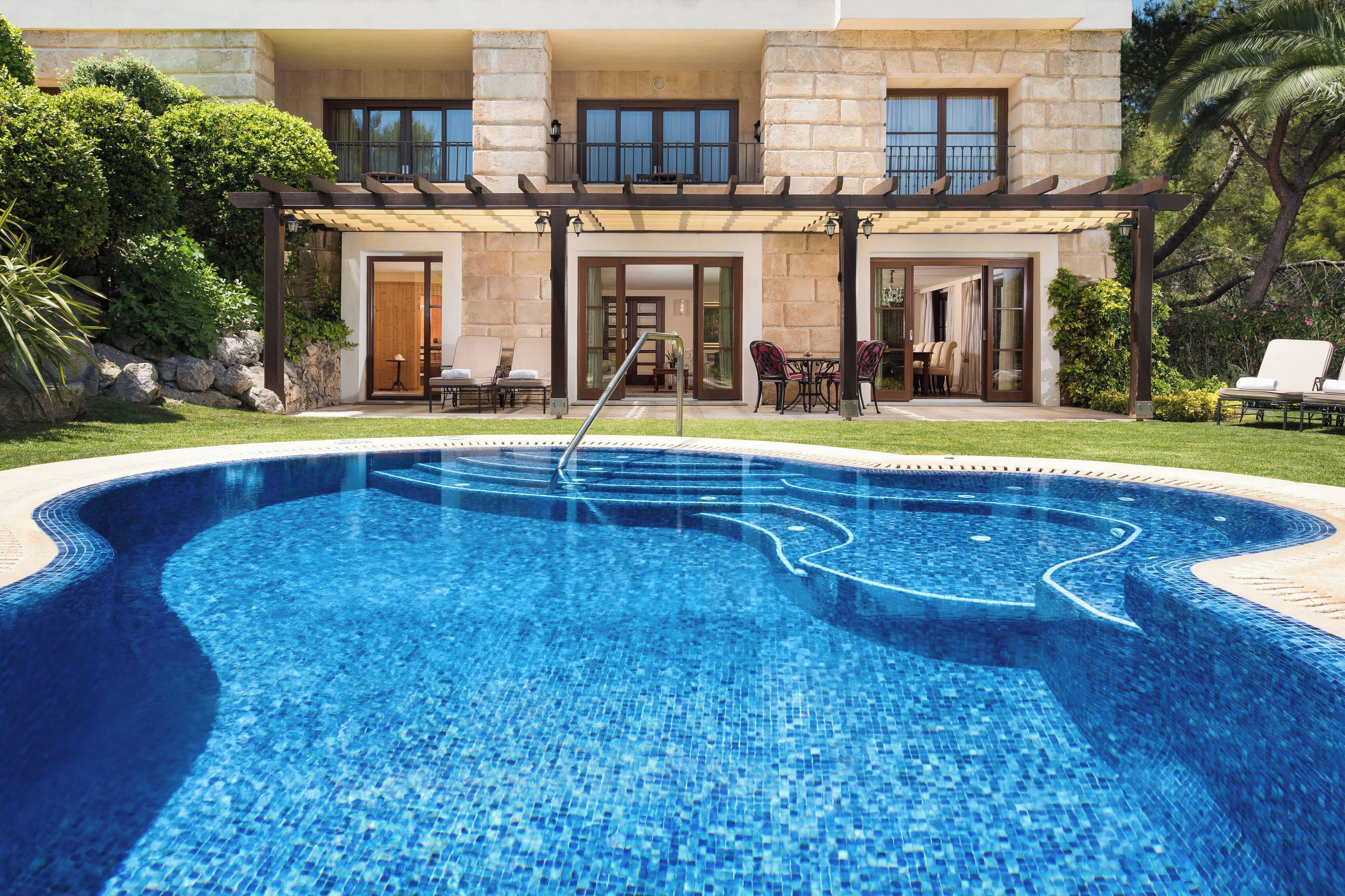 A swimming pool with a stone facade and a covered patio area.