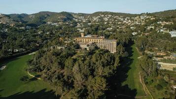 An aerial view of a large building surrounded by dense forest and a golf course.