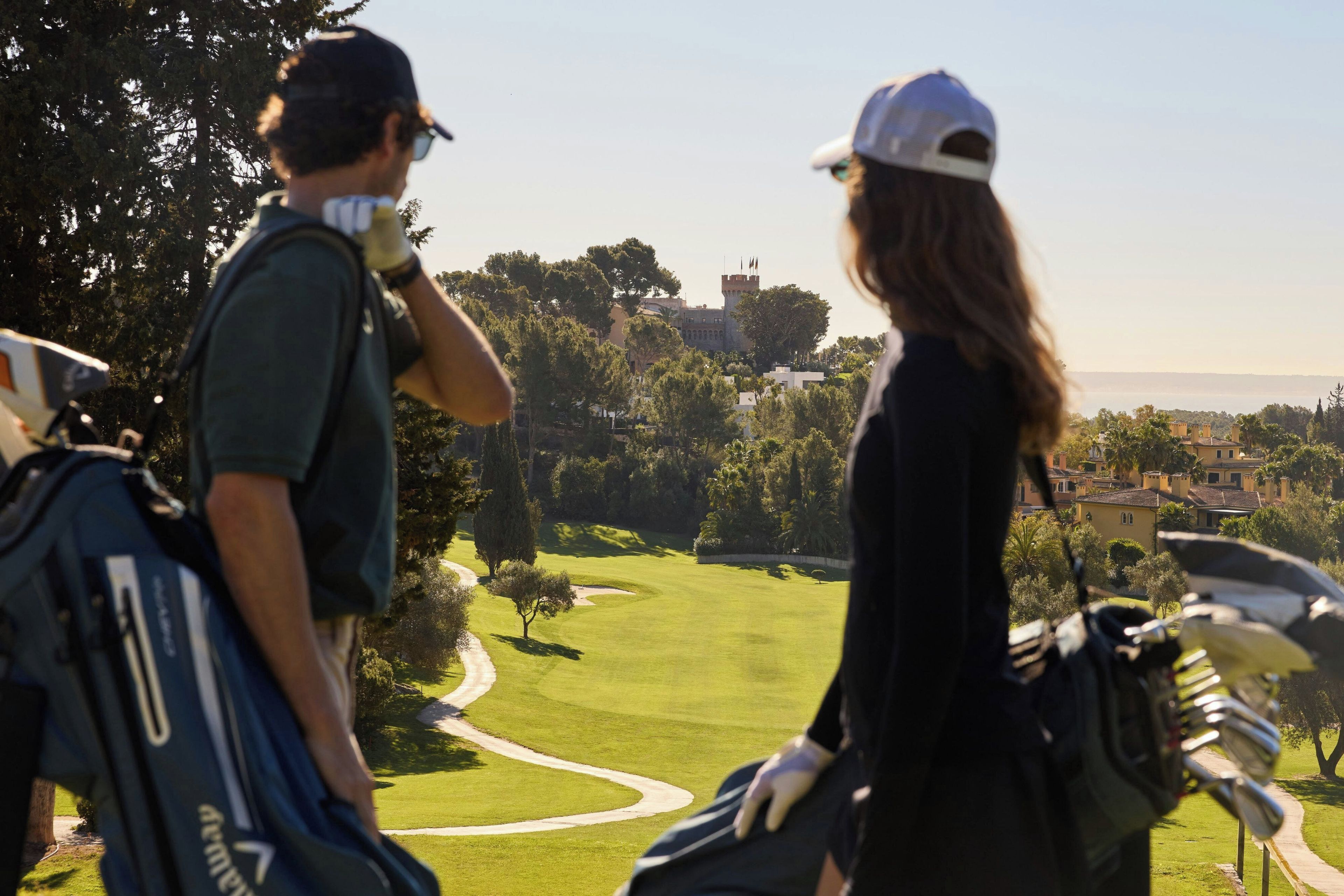 A golf course with a clear path, trees, and a distant building.