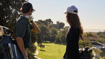 A golf course with a clear path, trees, and a distant building.