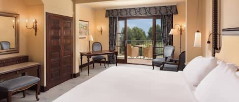 Habitación de hotel con una cama grande, un escritorio con una silla, un balcón con mesa y sillas, y vistas al exterior.