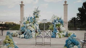 Decoración para boda al aire libre con un arco floral blanco y azul, dos columnas altas y un atril de metal.