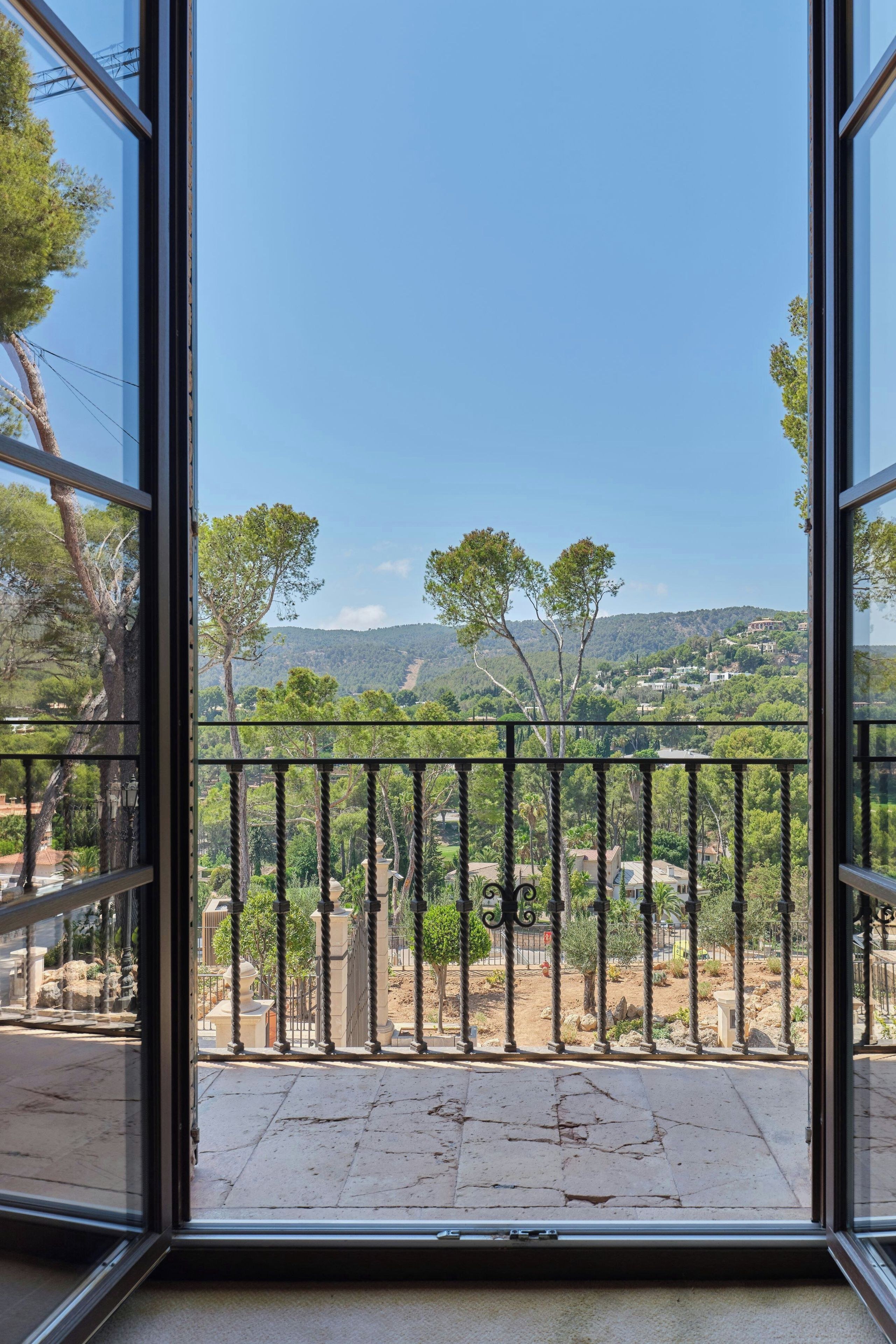 A balcony with a view of a mountainous landscape and trees.