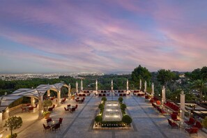 Une terrasse sur le toit, avec des chaises et des tables rouges, une fontaine centrale et une vue sur le paysage urbain.