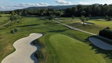 A golf course with sand bunkers, pathways, and trees.