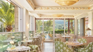 Ein Restaurant mit Tischen und Stühlen, großen Fenstern und Blick ins Freie.