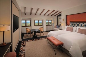 Habitación de hotel con una cama grande, un escritorio, una silla, una mesita y vistas al mar a través de las ventanas.