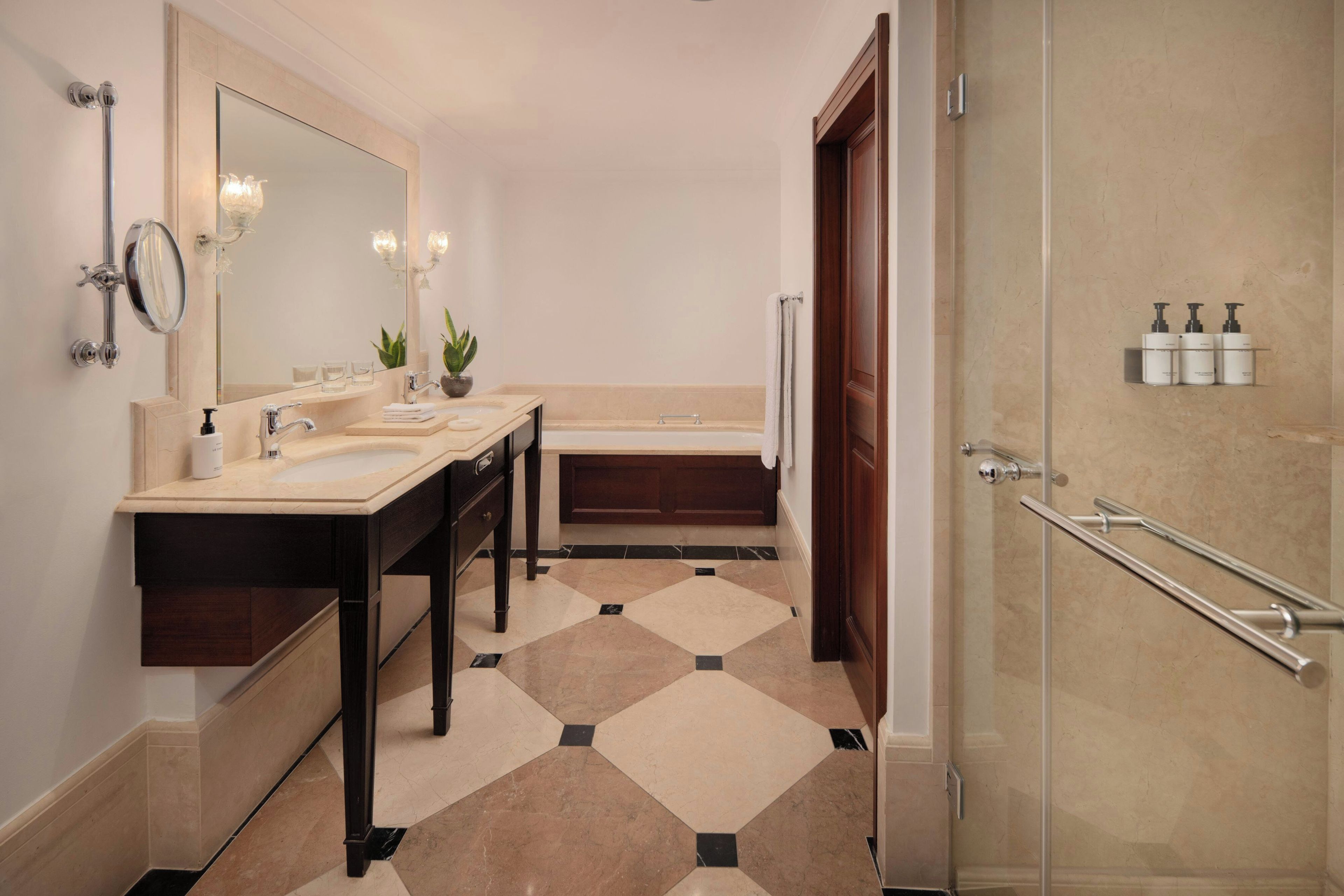 Een moderne badkamer met een dubbele wastafel, een grote spiegel, een badkuip en een douche.