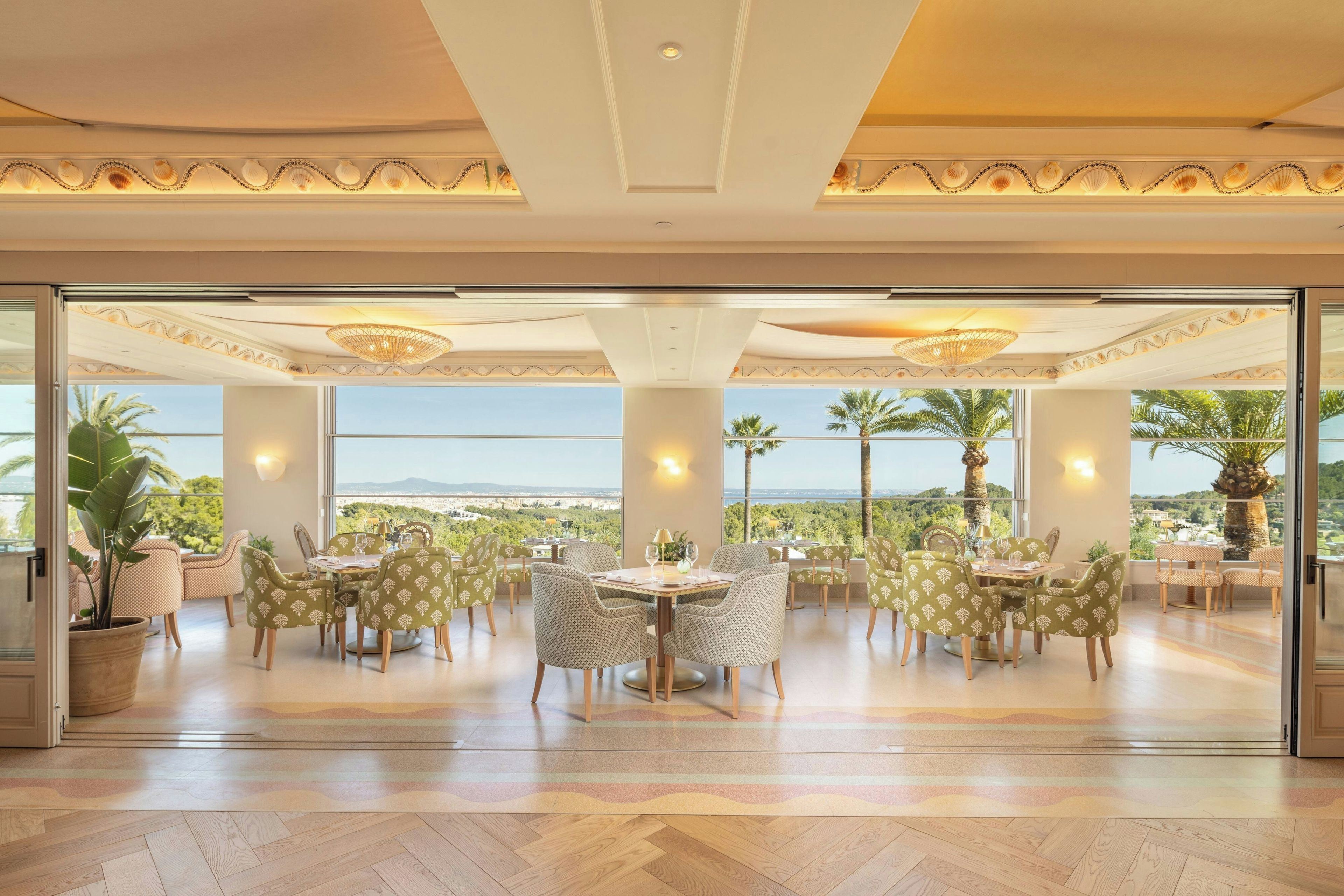 A spacious dining area with a large table and chairs, large windows with a view, and a ceiling with decorative moldings.