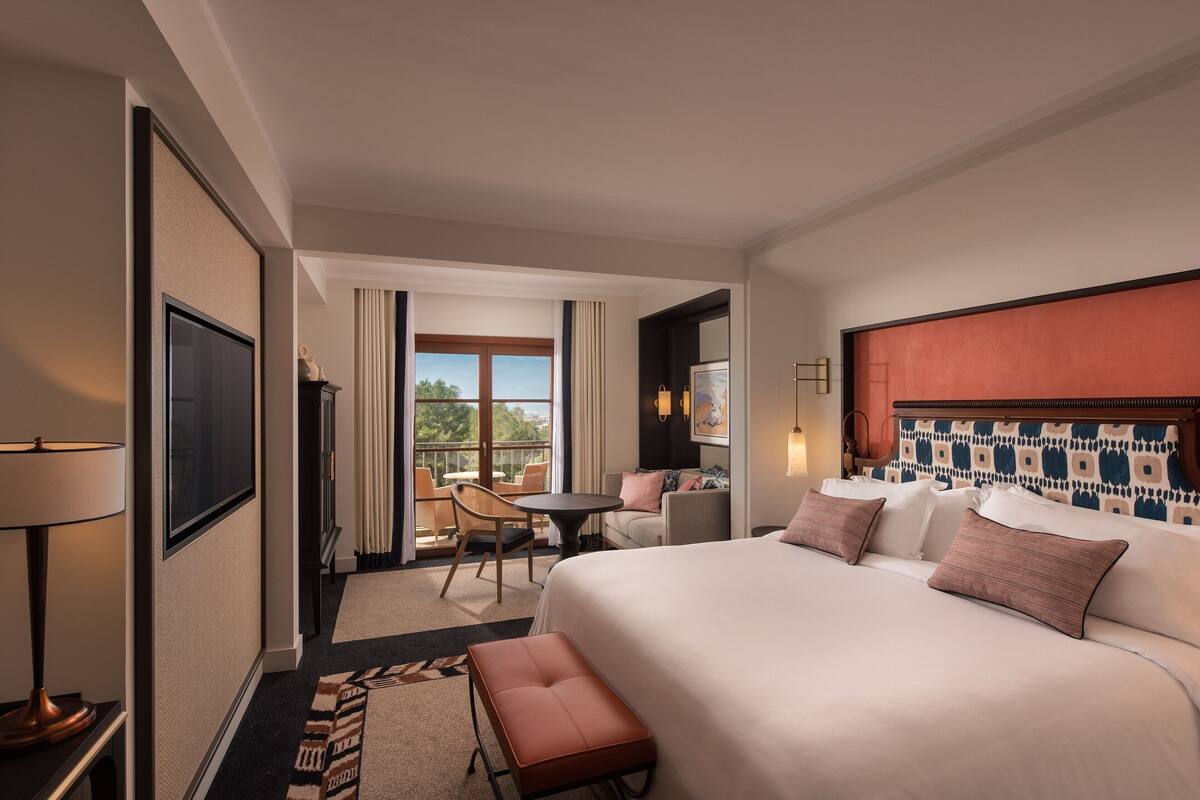 Une chambre d’hôtel avec un grand lit, une petite table, une chaise et une vue sur l’extérieur.