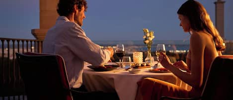 Un couple est assis à une table, profitant de la vue sur le paysage urbain.