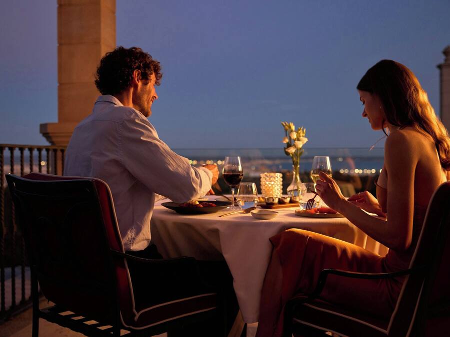 Una pareja cenando en una mesa con vistas a la ciudad.