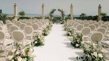 Un pasillo nupcial con sillas blancas y decoración floral.