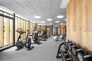 Ein Fitnessstudio mit Cardiogeräten, Gewichten und Trainingsbällen.
