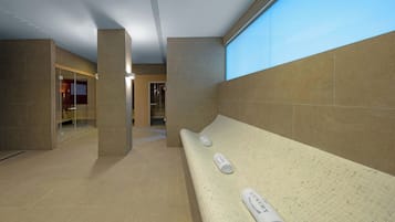 A modern interior with a long bench, two rolled towels, and a glass door leading to another room.