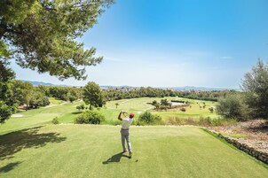 Un campo de golf con vistas despejadas del paisaje, incluyendo árboles y edificios al fondo.