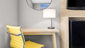 A room with a yellow chair, a desk, a lamp, a mirror, and a TV. - Days Inn by Wyndham La Crosse (La Crosse)