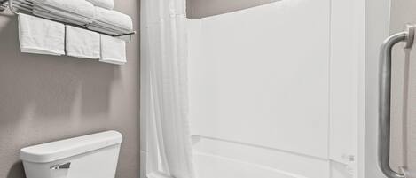 A bathroom with a toilet, a shower with a glass door, and a towel rack with folded towels.