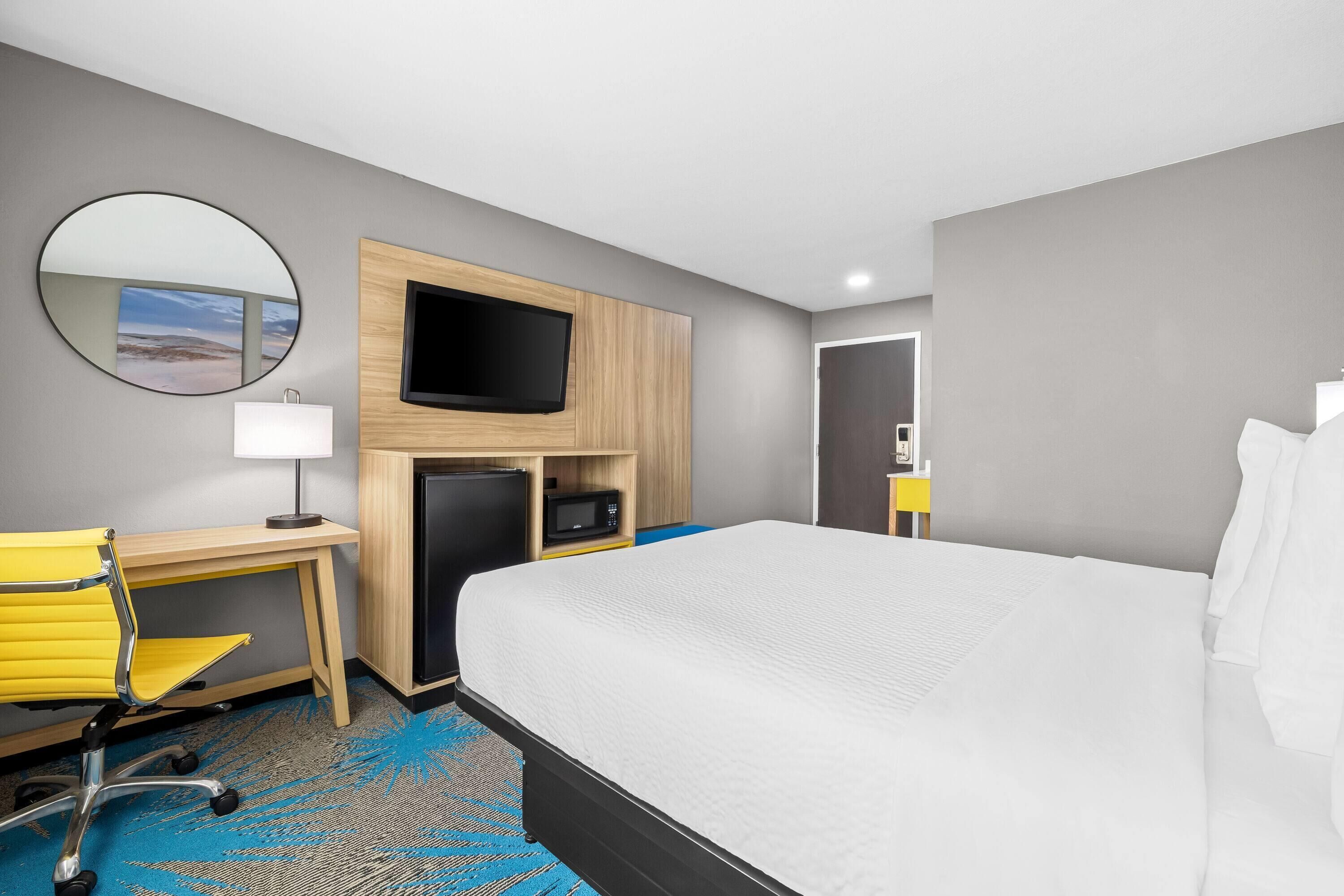 Une chambre d’hôtel équipée d’un lit, d’un bureau, d’une chaise, d’une télévision et d’un miroir.