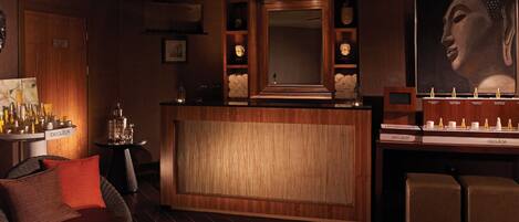 Un bar moderno con mobiliario de madera, una gran estatua de Buda y una zona de estar con un banco acolchado.