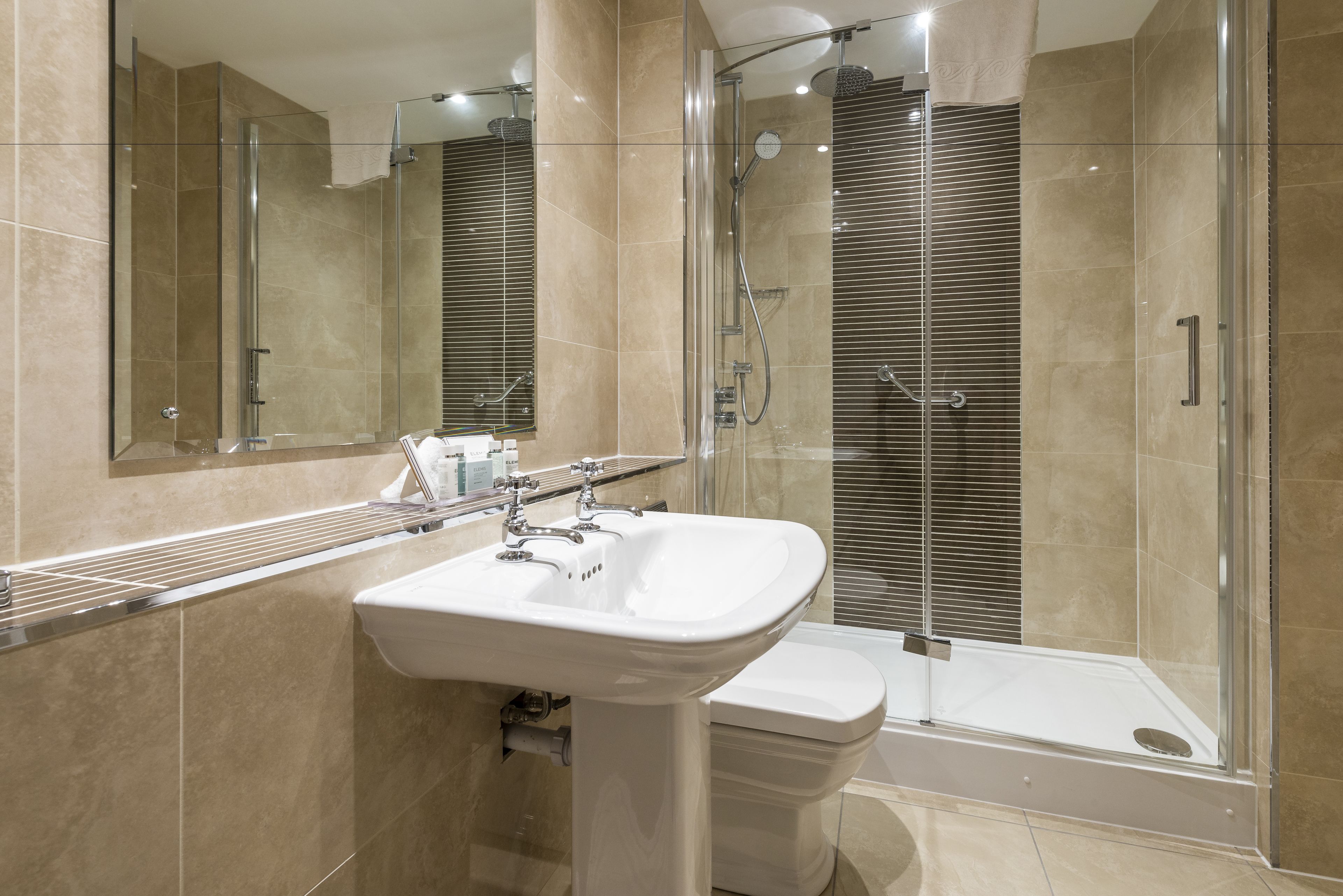 A modern bathroom with a glass-enclosed shower, a white sink, and a toilet.