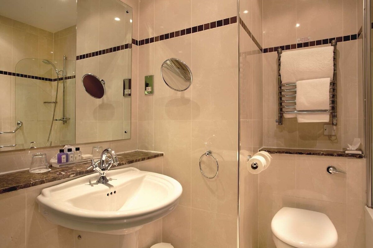 A bathroom with a sink, mirror, toilet, and shower.