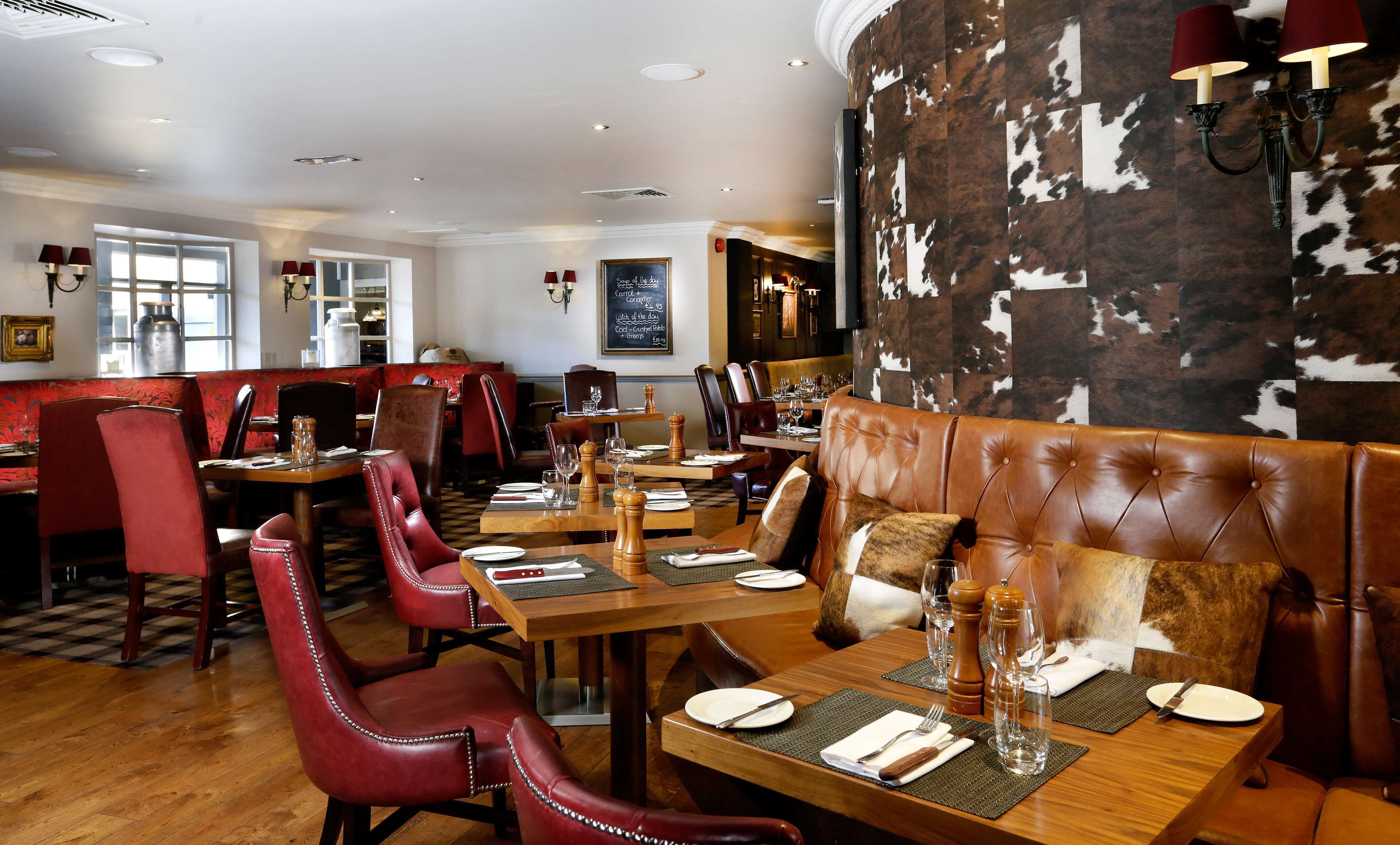 Un interior de restaurante con asientos de cuero, mesas de madera y una pared revestida de piel de vaca.