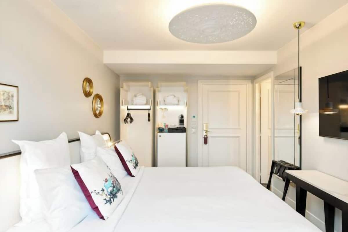 A hotel room with a large bed, a desk, a television, and a door leading to a bathroom.