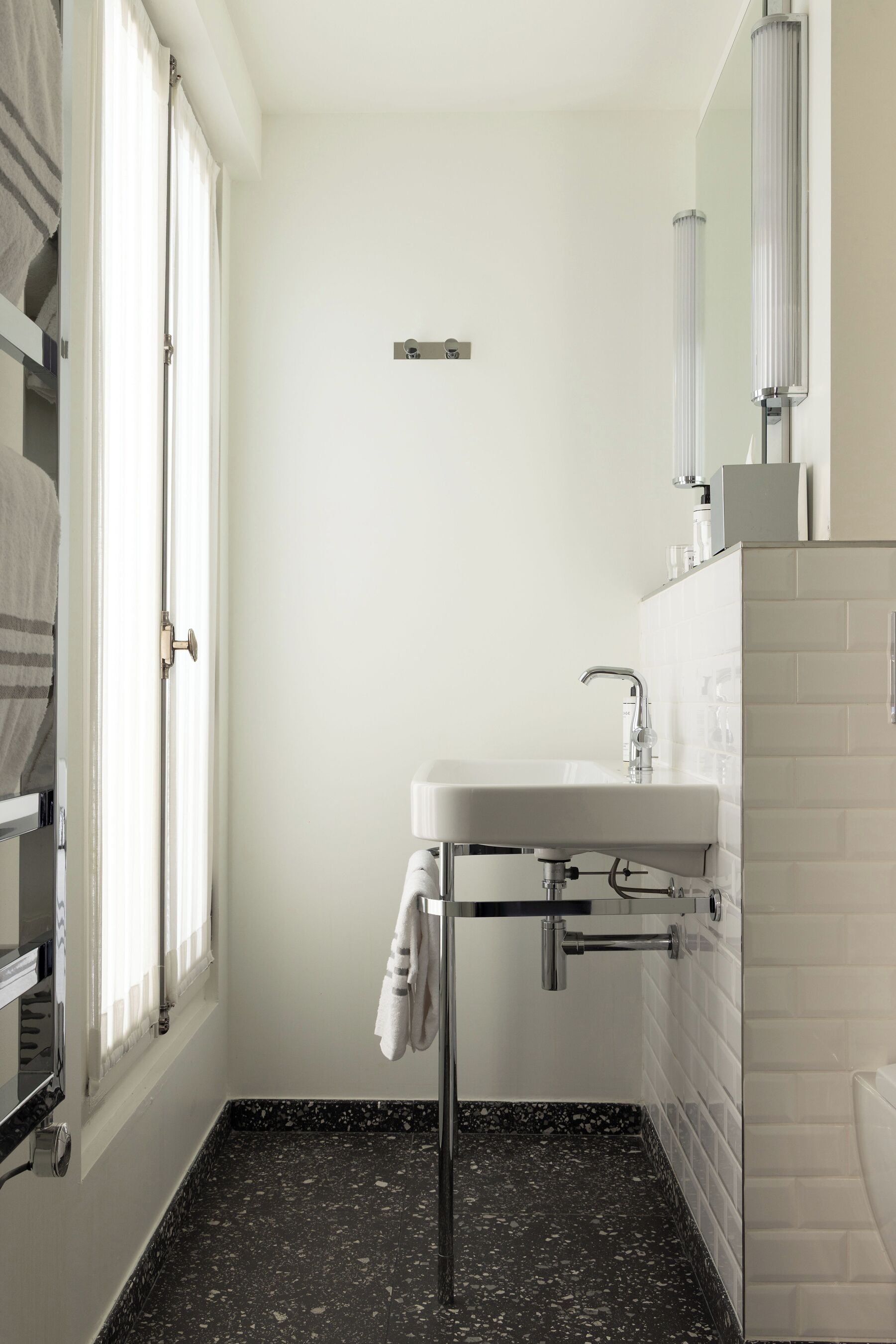 A bathroom with a white sink, a mirror, and a towel hanging on a rack.