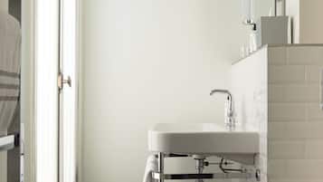 Une salle de bain avec un lavabo blanc, un miroir et une serviette suspendue à un porte-serviettes.