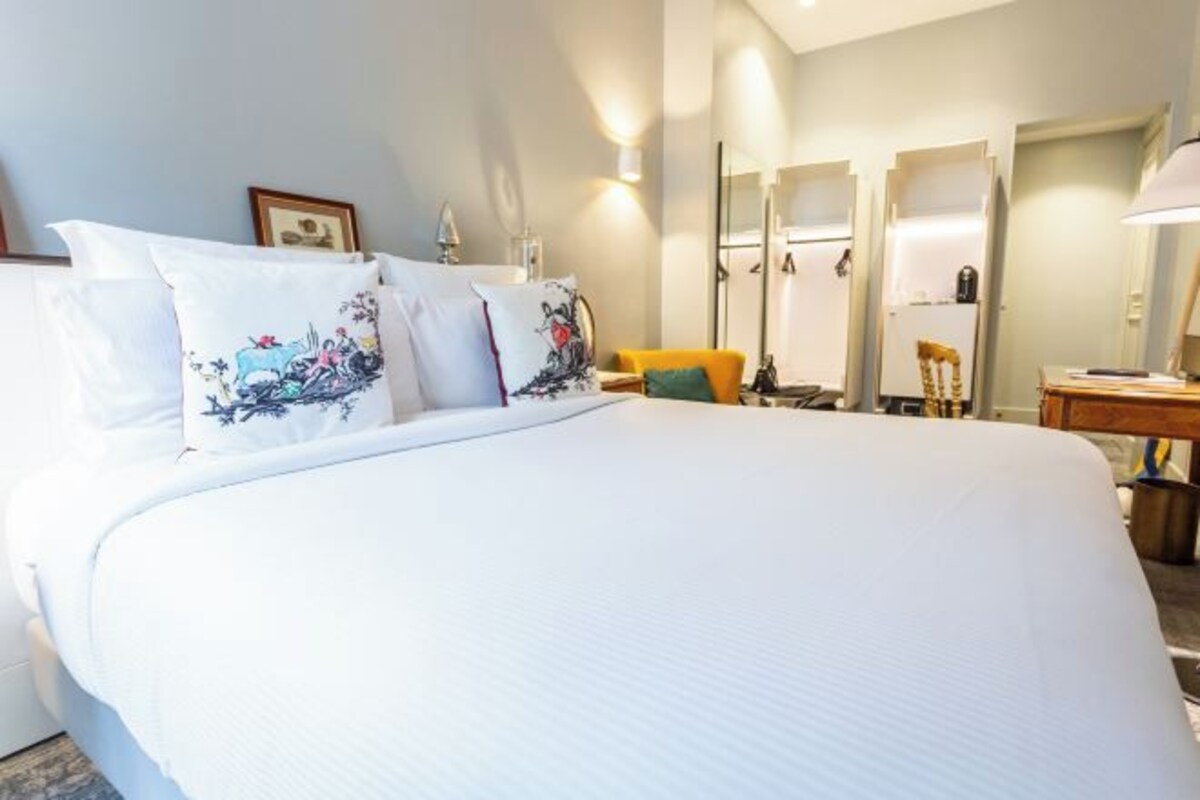 Een hotelkamer met een groot bed, een bureau, een stoel en een spiegel.