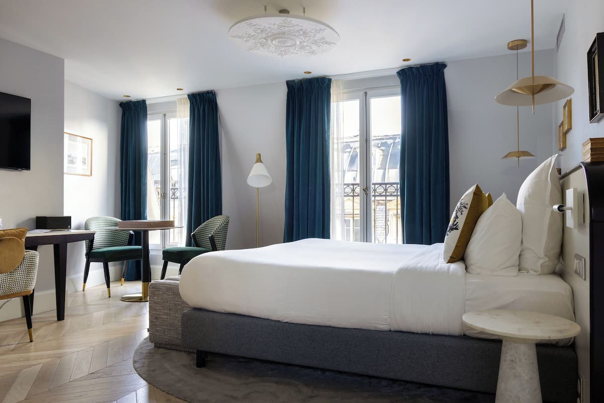 A modern hotel room with a large bed, a desk, and a chair.