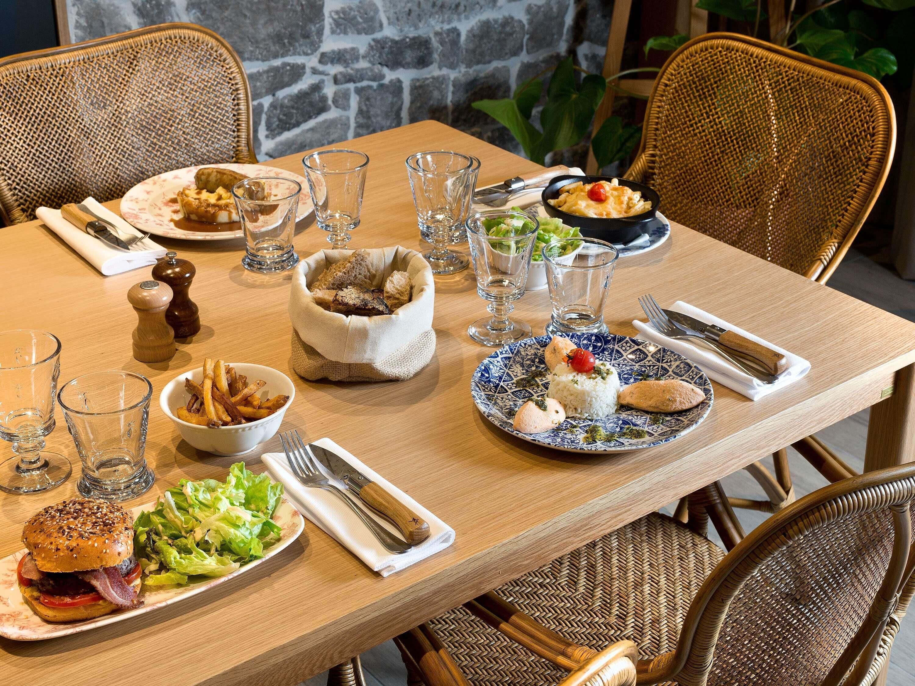 Een eettafel gedekt met verschillende gerechten, glazen en bestek.