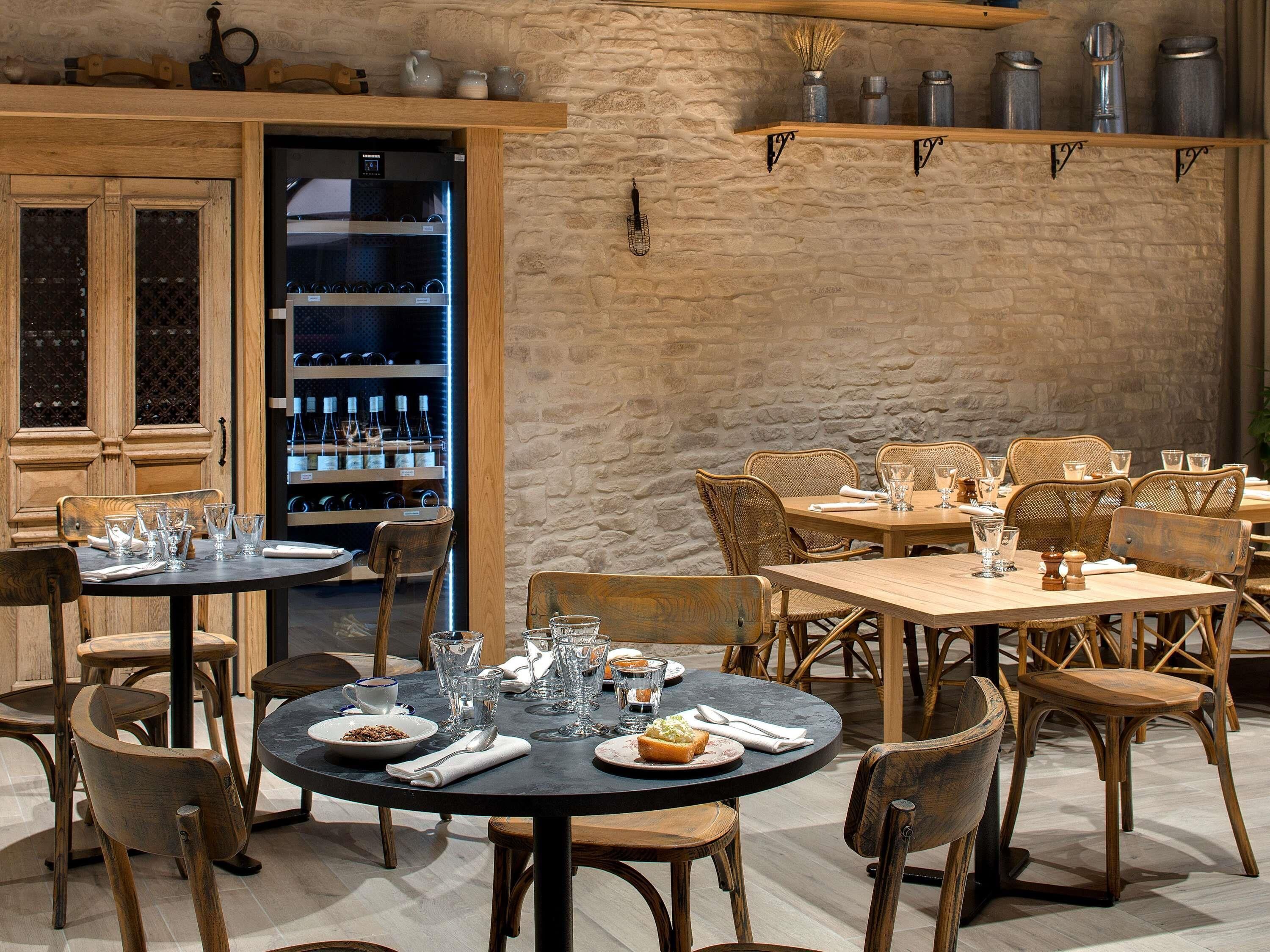 Interno di un ristorante con arredi in legno, pareti in pietra ed scaffali pieni di bottiglie.