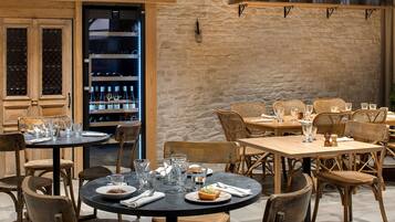 Interior de restaurante con mobiliario de madera, paredes de piedra y estantes con botellas.