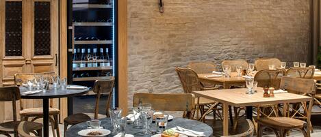 A restaurant interior with wooden furniture, stone walls, and shelves with bottles.