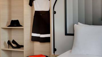 A hotel room with a bed, a nightstand, a framed picture, a wardrobe, and a mirror.