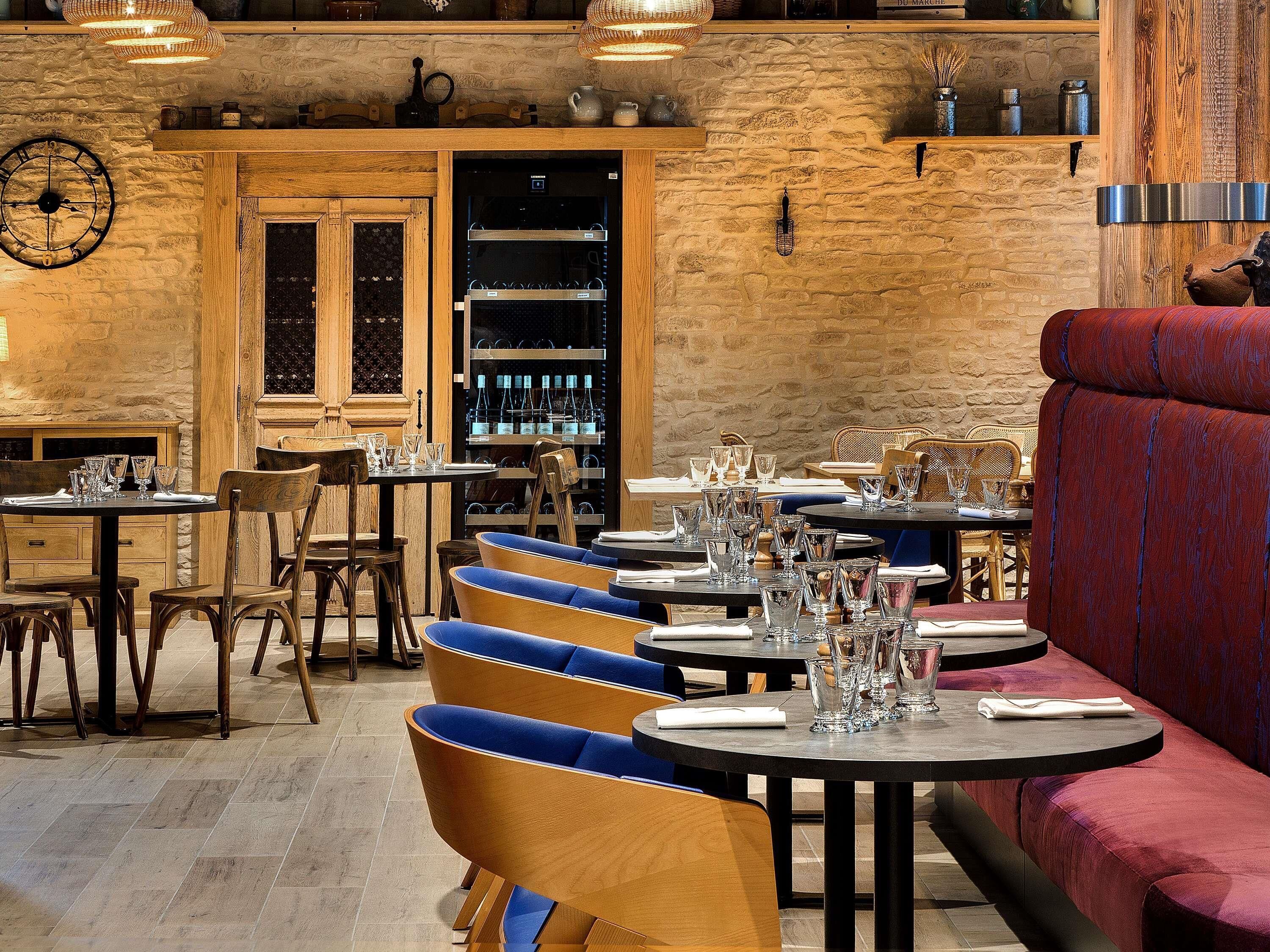 L’intérieur d’un restaurant avec des murs en bois, des tables rondes et des sièges bleus rembourrés.