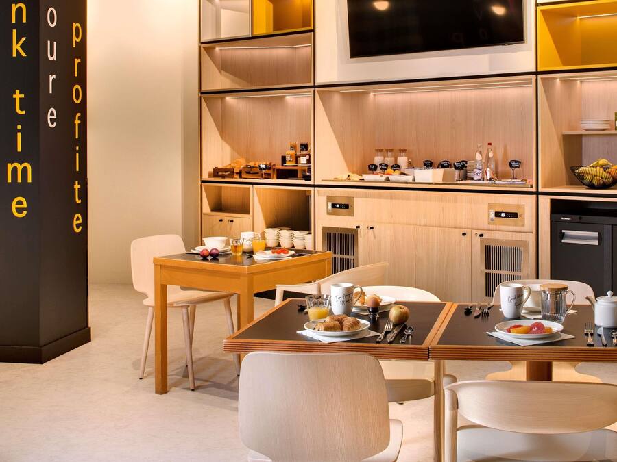 Une cuisine moderne avec des meubles de rangement en bois, une table à manger dressée avec des assiettes, des tasses et une bouilloire.