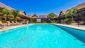 A swimming pool with lounge chairs and a lifeguard tower in the background. - Best Western Andersen's Inn (Gustine)