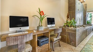 A reception desk with two Apple iMac computers, a printer, and a potted plant. - Best Western Plus Monterey Inn (Monterey)