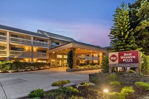 A hotel with a sign reading "Best Western Plus." It features a multi-story building with balconies and a landscaped entrance.
