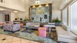 A spacious lobby with a stone wall, seating areas, and modern lighting fixtures. - Best Western Plus Monterey Inn (Monterey)